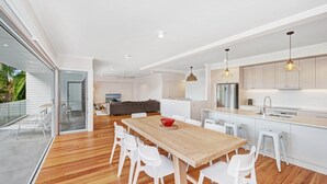 A modern kitchen with white cabinetry, a wooden dining table, and a large island with a sink.