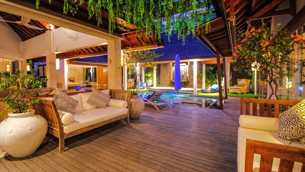 A covered outdoor area with a pool, lounge chairs, and seating arrangements.