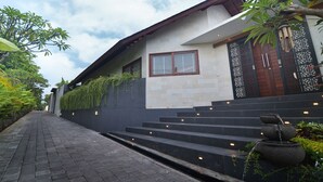 A modern house with a stone pathway leading to the entrance, a wooden door, and a decorative gate.