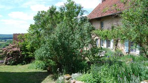 Ein rustikales Haus mit einer Steinwand und einem Garten mit verschiedenen Pflanzen und Blumen.