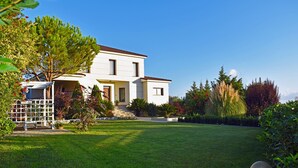 A two-story house with a white exterior, a front porch, and a well-maintained lawn. - Villa Komfort in Zakynthos suitable for family or group with private pool (Lagopodo,Zakynthos)