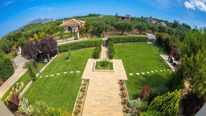 A landscaped garden with a central pathway, surrounded by well-maintained lawns and various shrubs. - Villa Komfort in Zakynthos suitable for family or group with private pool (Lagopodo,Zakynthos)