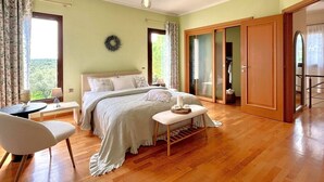 A bedroom with a bed, bedside table, chair, and a view of the outdoors. - Villa Komfort in Zakynthos suitable for family or group with private pool (Lagopodo,Zakynthos)