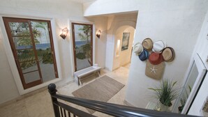 A spacious hallway with a bench, a wall-mounted hat rack, and a view of the ocean through a door. - Stunning, private villa on Barbados' Platinum west coast. (Gibbs)
