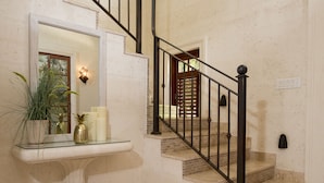 A staircase with a black metal railing, a white marble wall, and a small white pedestal with a mirror and candles. - Stunning, private villa on Barbados' Platinum west coast. (Gibbs)