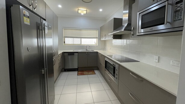 A modern kitchen with stainless steel appliances, white cabinets, and a tiled floor. - "Oxley House" - Scarborough Q 4020 (Scarborough)