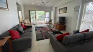 A living room with grey sofas, a television, and a large window. - "Oxley House" - Scarborough Q 4020 (Scarborough)