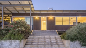 Un edificio moderno con un acceso cubierto, ventanas amplias y una escalera que conduce a la puerta.