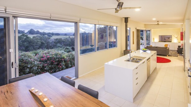 Una cocina moderna con una isla central, ventanas amplias y vistas a un jardín.