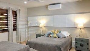 Een slaapkamer met een bed, nachtkastjes, een lamp, een kledingkast en een airconditioning.