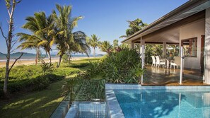 Un espace piscine avec vue sur la plage et les palmiers.