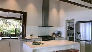 A modern kitchen with a central island, stainless steel appliances, and a large window.
