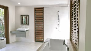 Een moderne badkamer met een bad, douche en wastafel.