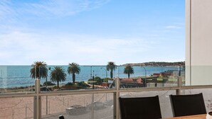 A balcony with a view of the sea, palm trees, and a distant shoreline. - The Penthouse with Views (Victor Harbor)