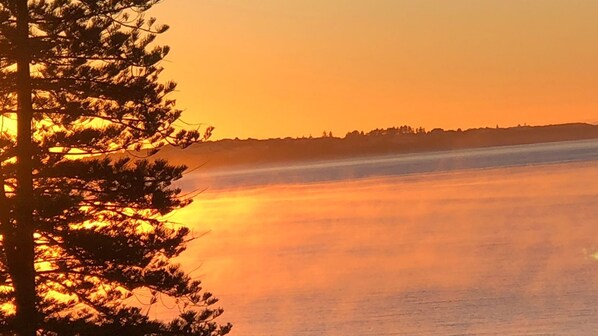 A coastal landscape with a body of water reflecting the sunset.