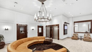 A spacious lobby with a curved leather sofa, a central chandelier, and a large mirror. - Sydney- CLD01 Bridge Street - Modern 1BR with Rooftop Pool in the Heart of Sydney CBD (Sydney)
