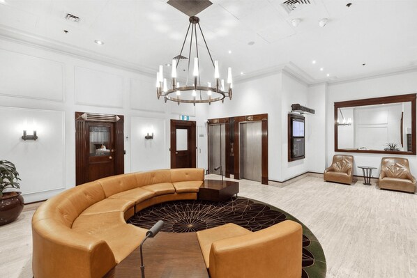 A spacious lobby with a curved leather sofa, a central chandelier, and a large mirror. - Sydney- CLD01 Bridge Street - Modern 1BR with Rooftop Pool in the Heart of Sydney CBD (Sydney)
