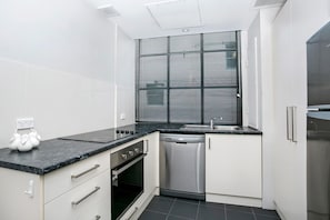 Enjoy cooking in this compact kitchen with a sleek countertop, oven, and stainless steel dishwasher.