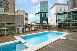 Enjoy a refreshing swim in our rooftop pool surrounded by a wooden deck and safety railings.