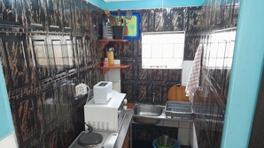 Une cuisine de taille réduite, équipée d’une cuisinière à gaz, d’un évier et d’une fenêtre.