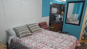 Une chambre à coucher avec un lit, des oreillers, une commode, un miroir et une petite table.