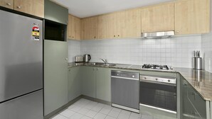 A modern kitchen with stainless steel appliances, wooden cabinets, and a tiled backsplash.
