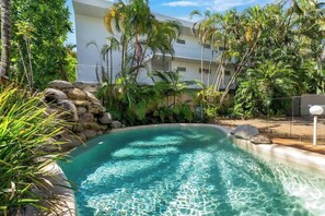 Una piscina circondata da vegetazione tropicale e un edificio a più piani.