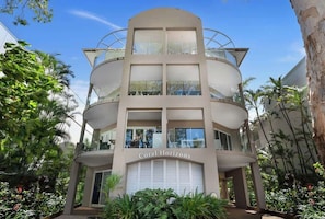A multi-story hotel with a curved facade, balconies, and a sign reading 'Coral Horizons'.