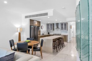 Une cuisine moderne dotée d’un îlot central, d’un coin repas avec des chaises et d’une horloge bien visible.
