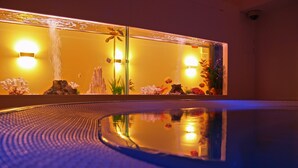 Une piscine dont le bord est texturé, agrémentée d’un élément décoratif aquatique et dont l’eau reflète les lumières et les décorations.