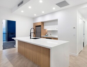 Una cucina moderna con isola centrale, mobili bianchi e vista sull'esterno.