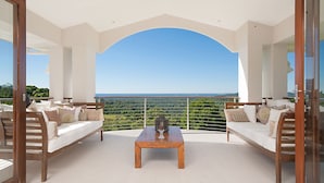 Ein Balkon mit Holztisch und zwei Sofas, mit Blick auf eine reizvolle Landschaft.