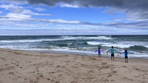 A beach with footprints in the sand and waves crashing onto the shore.