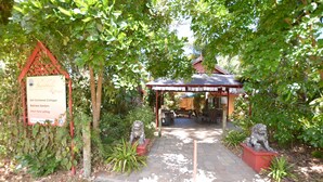 Un sendero conduce a una estructura cubierta con un jardín balinés y un cartel de un retiro.