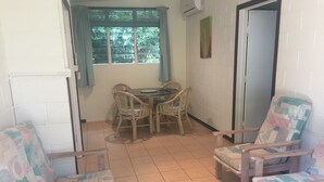 Una habitación con una mesa de comedor y sillas, una ventana con persianas, una puerta y un radiador.