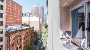 A view from a balcony with a cityscape, including a mix of modern and historic buildings, and a clear street below.