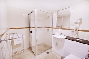Un bagno moderno con doccia vetrata, lavandino bianco e specchio sopra.