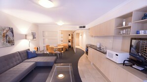 A modern living room with a sofa, coffee table, and dining area.