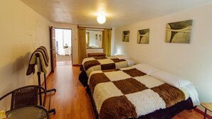 Ein Hotelzimmer mit zwei Betten, einem Sessel, einem Tisch und Bildern an den Wänden.