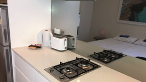 Una cucina compatta con due fornelli a gas, un tostapane e un bollitore.