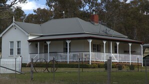 A two-story house with a porch, a chimney, and a fenced yard.