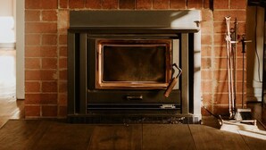 A brick fireplace with a clock above it.