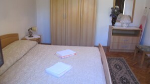 Ein Schlafzimmer mit Bett, Nachttisch, Kommode, Spiegel und Kleiderschrank.