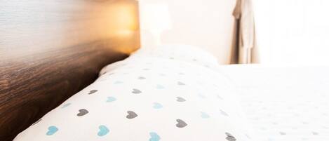 A neatly made bed with patterned bedding, a wooden headboard, and a window with curtains.