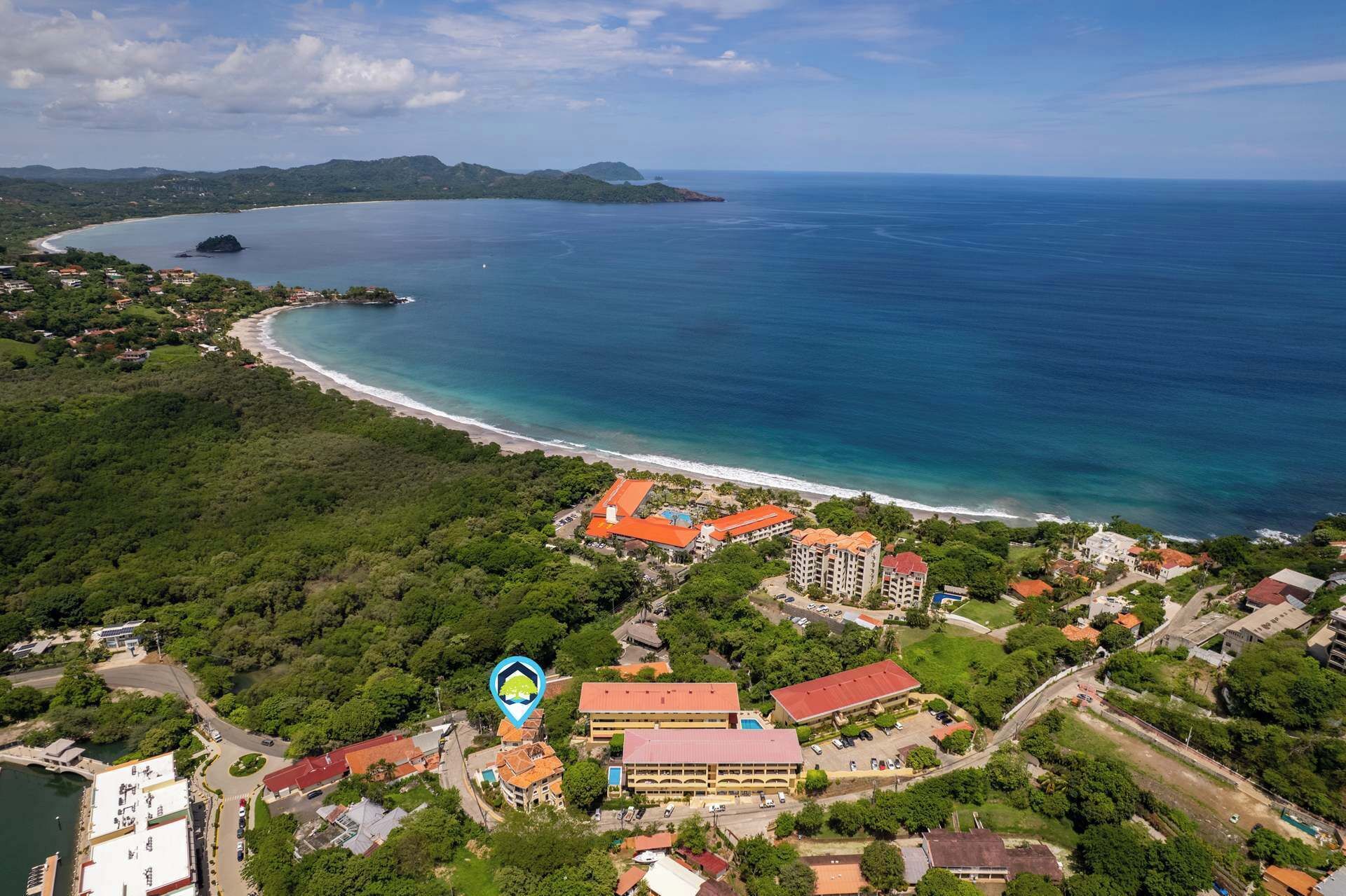 An aerial view of a coastal area with a beach, buildings, and a large body of water.