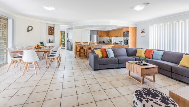 A spacious living area with a dining table, sofa, and kitchen in the background. - Kidman Place - Spacious Luxury+ FREE WIFI + WINE (Brisbane North)
