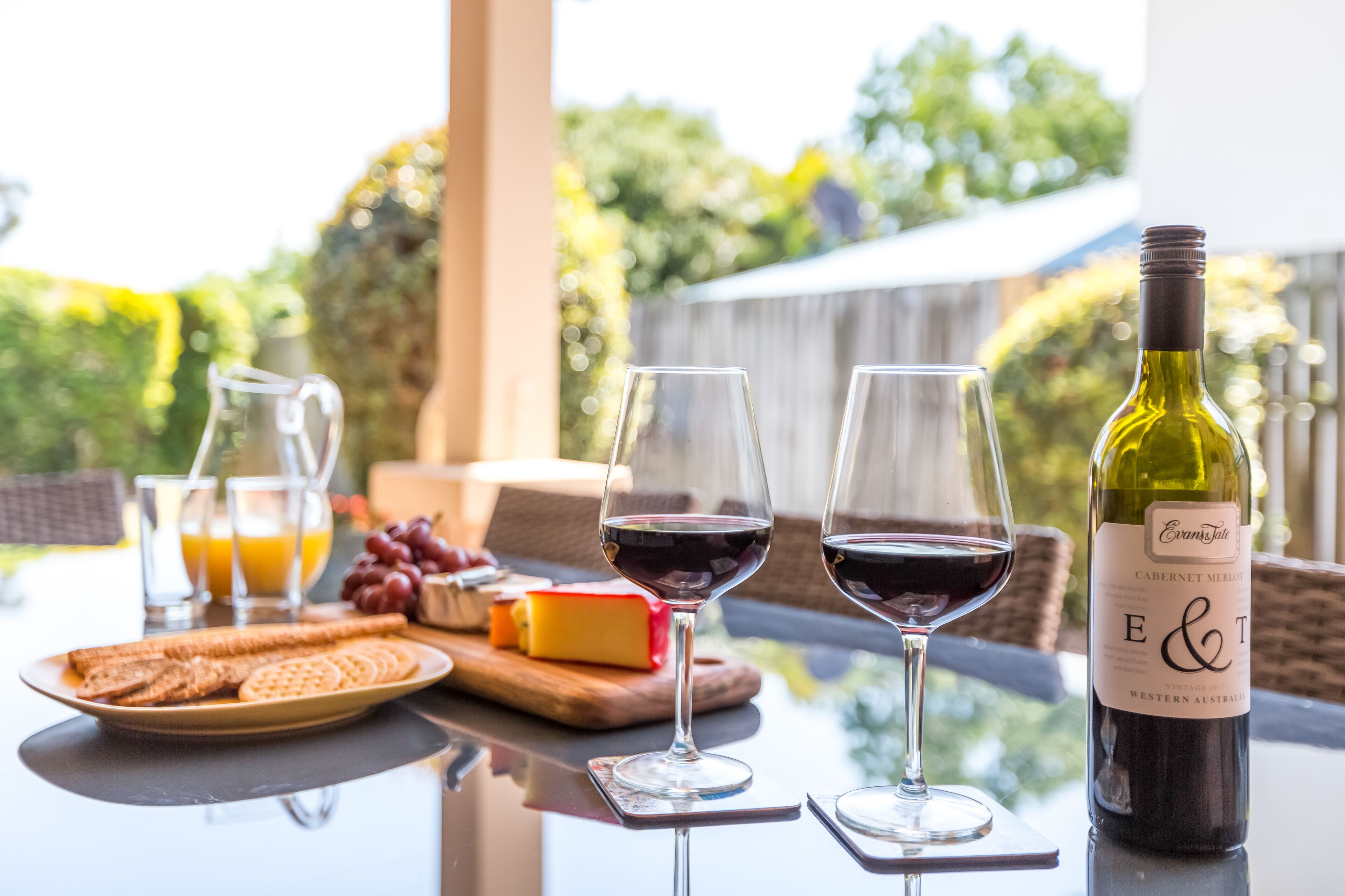 A table with two wine glasses, a bottle of wine, a glass of orange juice, and some snacks.