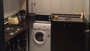 Eine kompakte Küche mit Waschmaschine, Mikrowelle und Spüle.