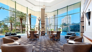 A spacious lobby with large windows, a pool view, and a modern interior design.