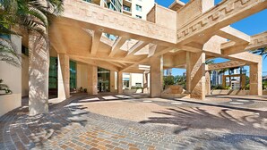 A spacious outdoor area with a modern architectural design, featuring large stone columns and a paved walkway.